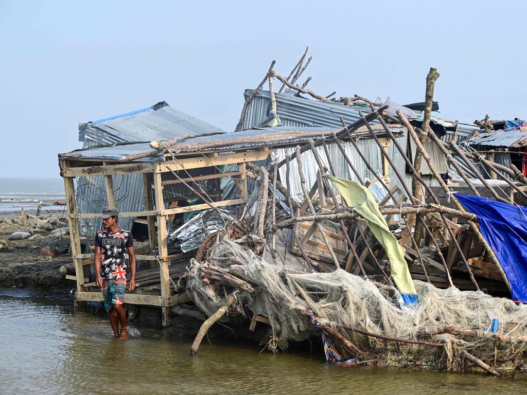 A man walks past a damaged shop after cyclone Remal's landfall.