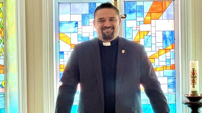 Father Dan Hobbs in a chapel with stained-glass at the Anglicare residential aged care home.