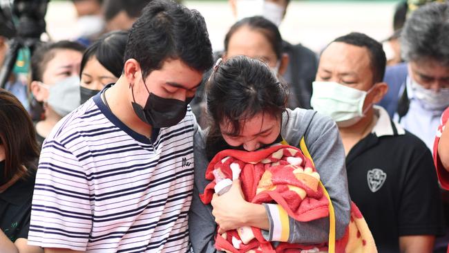 Sittipong Taothawong comforts his wife Kanjana Buakumchan as she holds their dead child's milk bottle and blanket while standing outside the nursery in Thailand's northeastern Nong Bua Lam Phu. Picture: AFP