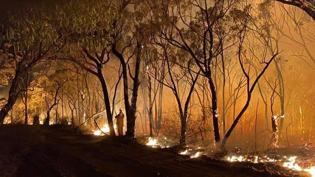 A strike team of volunteer firefighters backburning terrain.