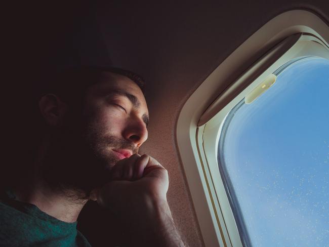 Young man resting and sleeping on an airplane.
