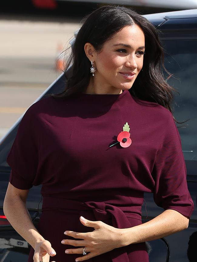 Meghan wore a burgundy Hugo Boss dress when boarding the plane for New Zealand. Picture: AAP Image/Steve Christo