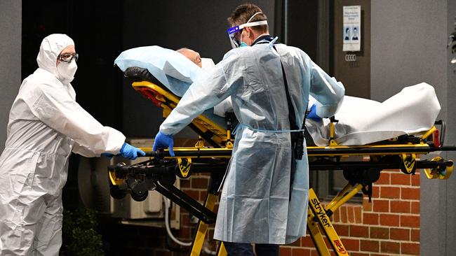 Healthcare workers transport a person into a patient transport vehicle at the Arcare Maidstone nursing home in Melbourne’s west on Wednesday. Picture: AAP