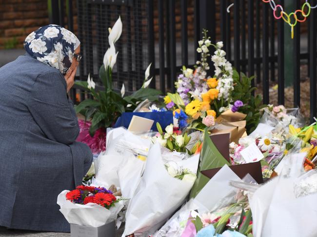 A woman places flowers outside Banksia Road Public School in Greenacre.