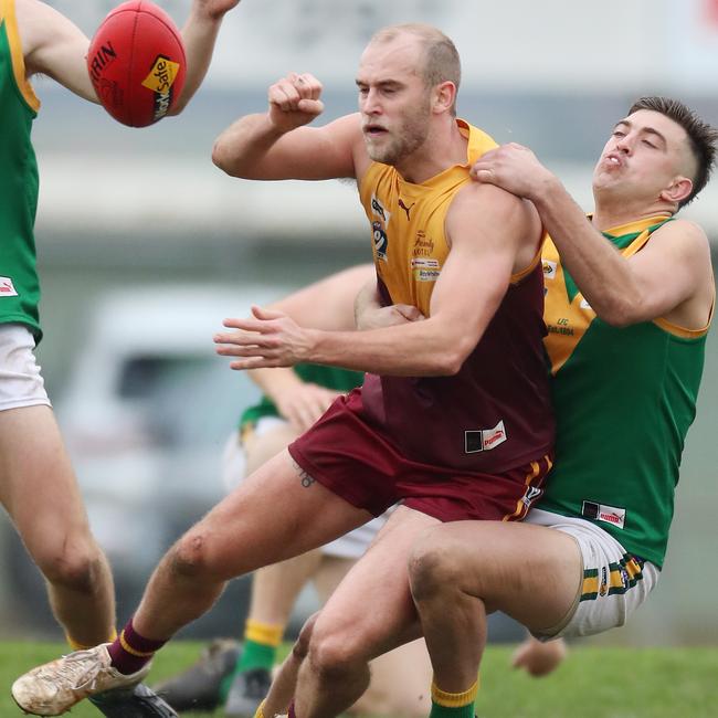 Drouin captain Jarrod Marshall fires off a handball as he is tackled by Leongatha’s Jacob Lamers.