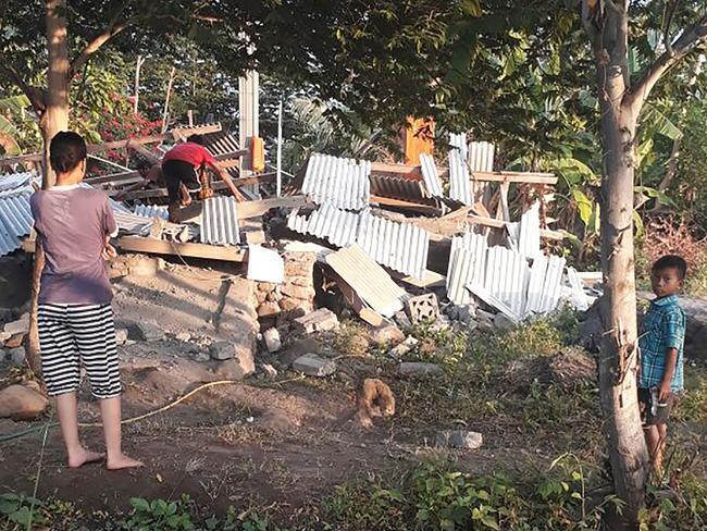 This photo released by the Nusa Tenggara Barat Disaster Mitigation Agency shows a resident scrambling over the collapsed ruins of a house.