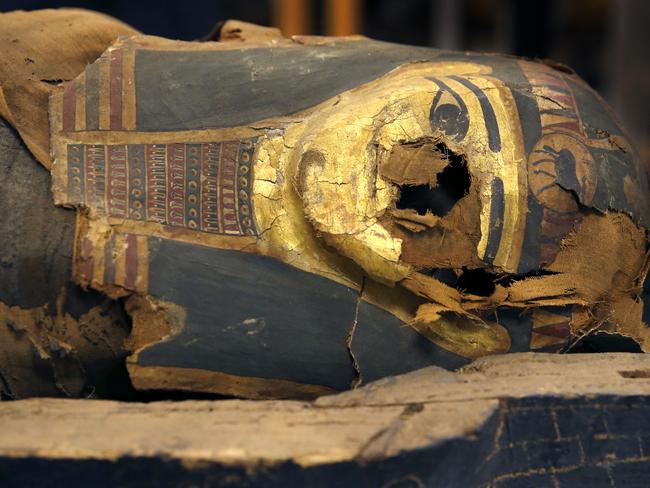 In this photo taken Friday, Dec. 5, 2014, in Chicago, the mummified body of Minirdis, a 14-year-old Egyptian boy and his burial mask lie in his opened coffin after J.P. Brown and his team of curators at the Field Museum opened the coffin for the first time. Brown and his team will begin conservation work on the 2,500-year-old boy before it becomes part of a traveling exhibition. Brown says they have to fix his burial mask, shroud, reconnect his detached feet, and do work to shore up the coffin and mummy so they can withstand travel. (AP Photo/Charles Rex Arbogast)