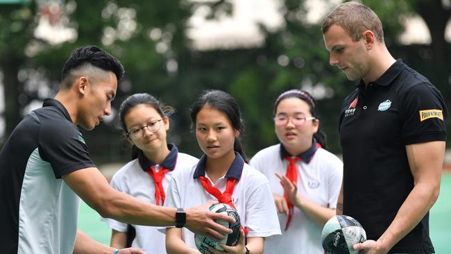 Port Adelaide player Chen Shaoliang, left, and Australian Olympic gold medallist swimmer Kyle Chalmers instruct schoolchildren on the finder points of Aussie rules during a primary school visit in Shanghai, China on Friday. Picture: AAP Image/David Mariuz