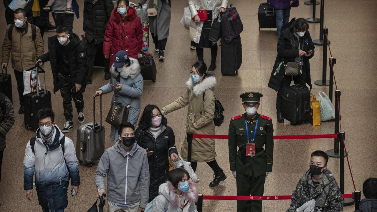 A Chinese police officer wears a protective mask as passengers arrive to board trains at a Beijing railway station. Picture: Kevin Frayer/Getty Images.