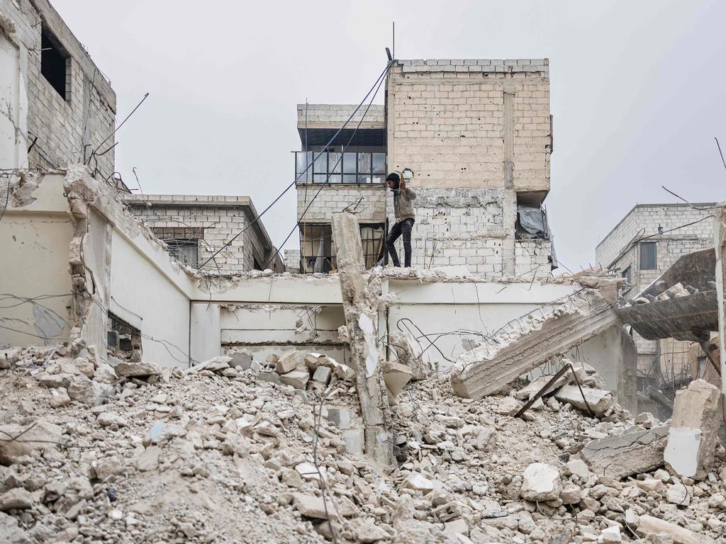 A youth walks by the rubble of a destroyed building being demolished in the city of Douma on the eastern outskirts of Damascus on December 22, 2024. Islamist-led rebels took Damascus in a lightning offensive on December 8, ousting president Bashar al-Assad and ending five decades of Baath rule in Syria. (Photo by Sameer Al-DOUMY / AFP)