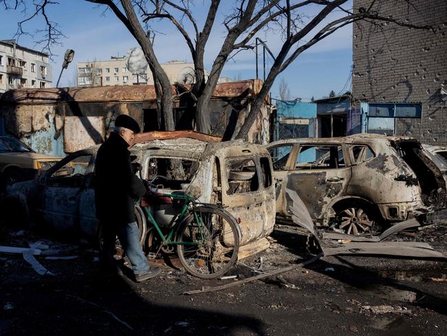 A man with a bicycle stands near burned cars following a strike in Dobropillia, Donetsk region. Picture: Tetiana Dzhafarova/AFP