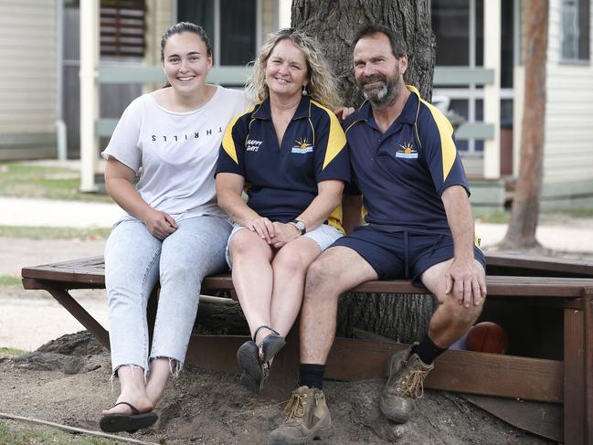 Victorian Fires Special. Mallacoota fire recovery feature. Mallacoota Beachcomber Caravan Park owners Debbie and Paul Preston with their daughter Demi, sit under the tree that was used as an orientation point when the fire hit and day turned to night.