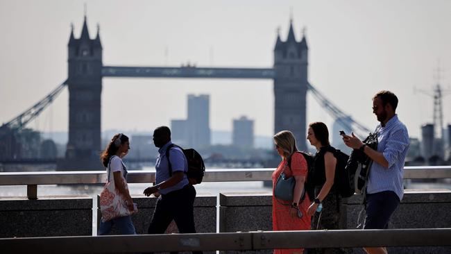 Office workers without facemasks cross London Bridge in London.