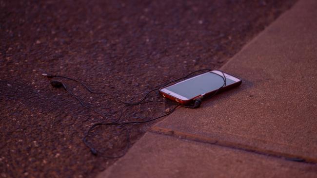 A phone and headphones were left on the street beside the footpath. Picture: Jay Town