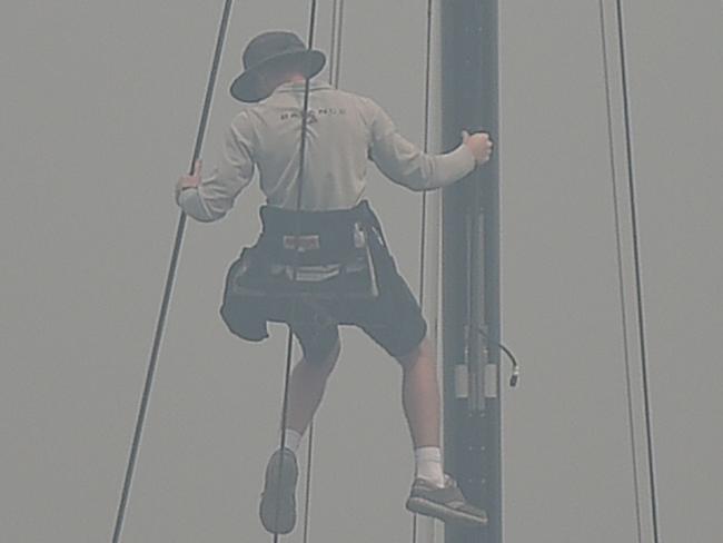 A sailor climbs the mast of a yacht enveloped in haze caused by nearby bushfires at the Cruising Yacht Club of Australia in Sydney on December 10, 2019. - The SOLAS Big Boat Challenge was cancelled after thick bushfire smoke sent visibility plummeting on Sydney Harbour. (Photo by PETER PARKS / AFP)