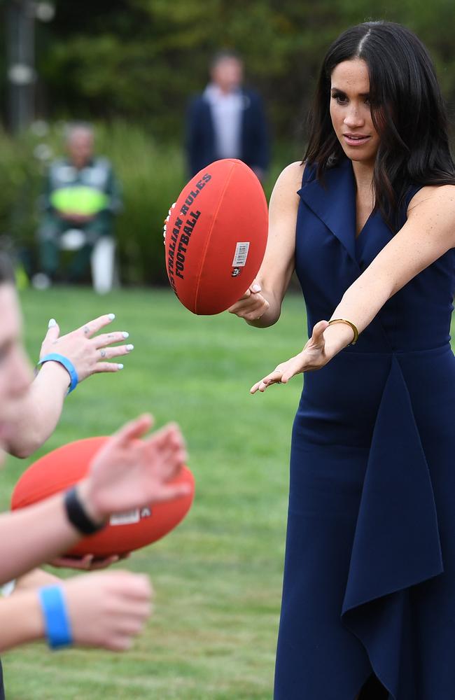 Meghan tries a bit of Aussie Rules in Melbourne on day three of her busy tour. Picture: Julian Smith