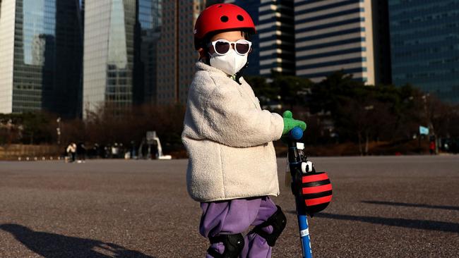 A South Korean child wears a mask to prevent catching coronavirus while riding outside. Picture: Chung Sung-Jun/Getty