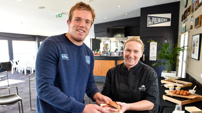 Sarah Jackson, from Sassy Chef, handing a rare bacon roll to Jake Trbojevic. Picture: Grant Trouville