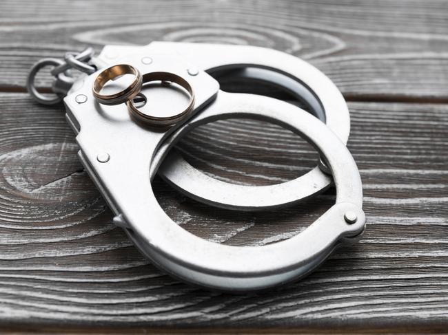 handcuffs, wedding rings on a wooden background. family law.