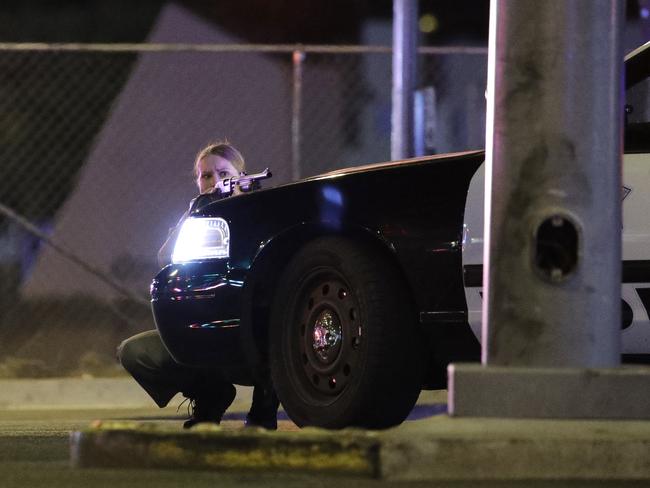 A police officer takes cover behind a police vehicle during a shooting near the Mandalay Bay resort and casino on the Las Vegas Strip. Picture: AP /John Locher