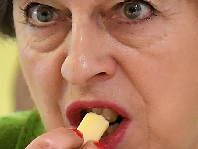 Britain's Prime Minister Theresa May samples a piece of cheese during a general election campaign visit to the Royal Bath and West Show in Shepton Mallet, south-west England on May 31, 2017, as campaigning continues in the build up to the general election on June 8. / AFP PHOTO / POOL / Leon Neal