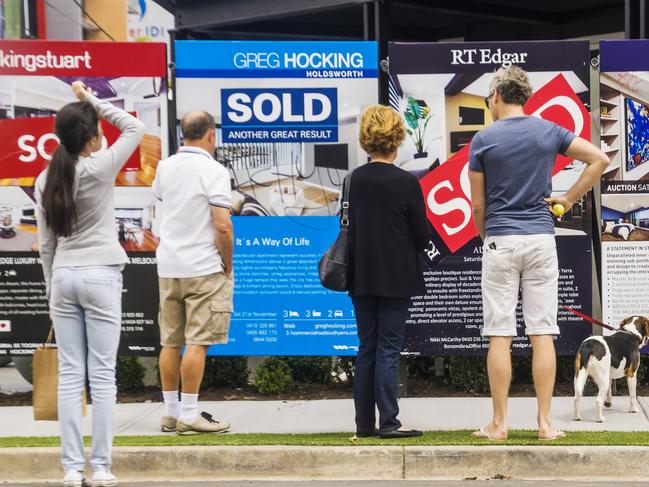 Melbourne, Australia - November 28, 2015: Visitors reading a row of estate agent signs outside a newly-renovated apartment building at 5 Commercial Rd, South Yarra. Formerly a derelict hotel, the site was the focus of Series 11 of popular Channel Nine TV series The Block. a reality renovation contest.