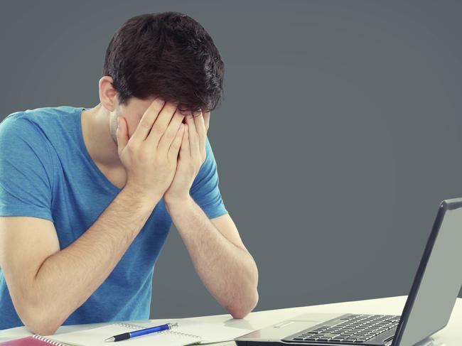 Tired of studying. young man covering his head while sitting. gesture of depression. Student failure for Greg Whitby column wk 44.