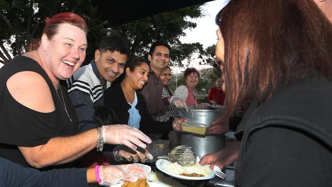 Shirlian Noy (red hair left side) and volunteers for her charity Helping Hands serve the homeless a special Indian feast at Lenfox Park Labrador. Picture Glenn Hampson