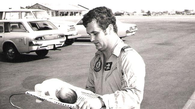 Flight Lieutenant Ian Frame carrying a baby in the aftermath of Cyclone Tracy. Picture: Supplied.