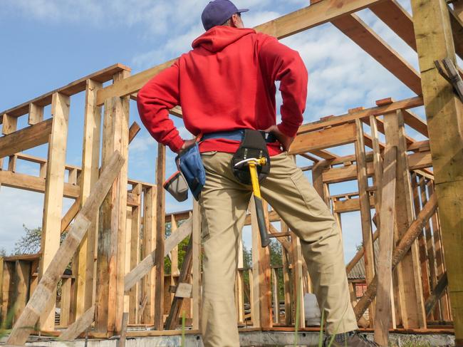 Developing Queensland - roofer, carpenter working on roof structure at construction site.