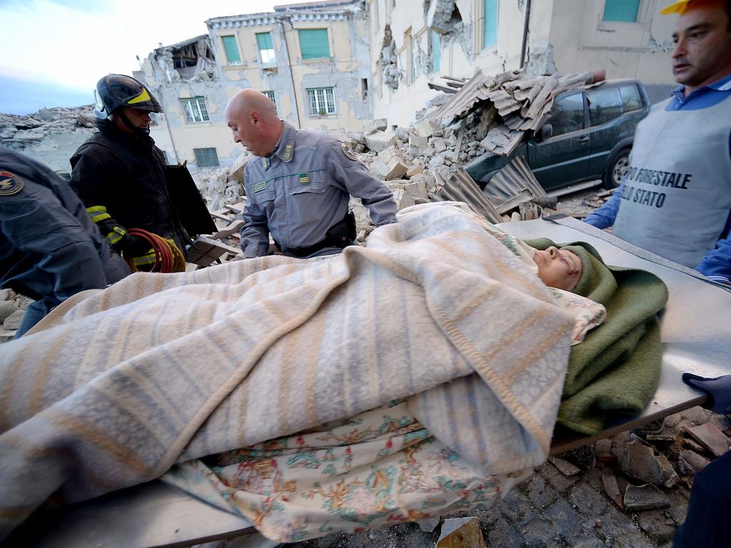 Rescue crews carry a man in Amatrice on August 24, 2016 after a strong earthquake. Picture: AFP