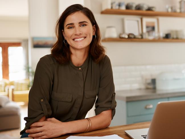 Cropped portrait of an attractive young woman smiling while   using a laptop to work from home