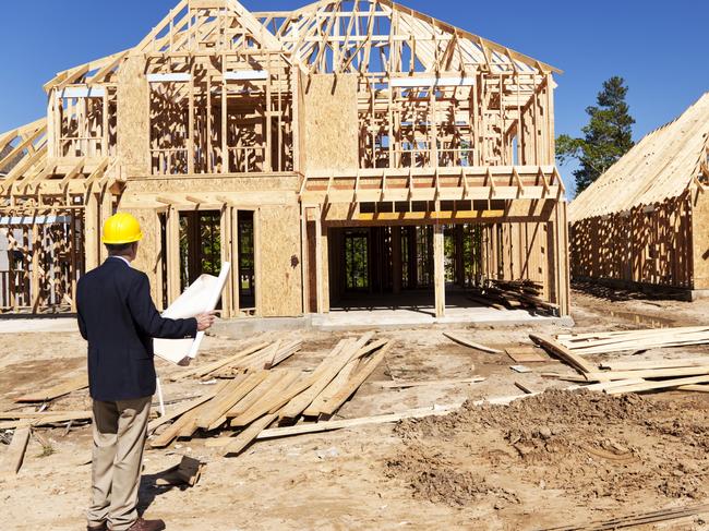 Developing Queensland - New home construction site with contractor in foreground.