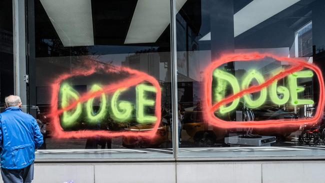 Members of the climate protest group, Extinction Rebellion, spray paint anti-DOGE messages on the outside of a Tesla showroom on April 22, 2025 in New York City. (Photo by STEPHANIE KEITH / GETTY IMAGES NORTH AMERICA / Getty Images via AFP)