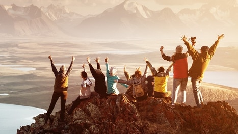 Big group of people having fun in success pose with raised arms on mountain top against sunset lakes and mountains. Travel, adventure or expedition conceptEscape 12 May 2024Doc HolidayPhoto - istock