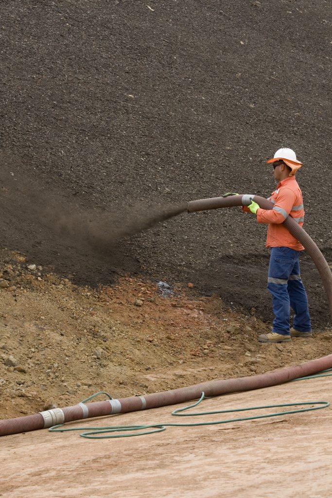 Peni Toia sprays the seed-laced mulch on the roadside. Picture: Kevin Farmer