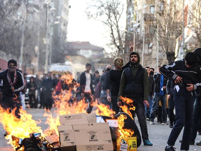 Protestors stand next to a fire during clashes between Turkish forces and Kurdish people in the centre of Diyarbakir, as they protest against the curfew in the Sur district of Diyarbakir, on March 2, 2016. Ankara has repeatedly imposed curfews for military operations in southeastern urban centres, in a measure the government says is necessary to root out PKK militants who were taking de-facto control in some areas. The Cizre curfew was one of the longest but a lockdown has also been in place since December 2 in the central Sur district which is home Turkey's biggest Kurdish majority city, Diyarbakir. According to the HDP, 25 citizens have been killed during the Sur curfew while several centuries-old historic and religious buildings have been destroyed. / AFP / ILYAS AKENGIN