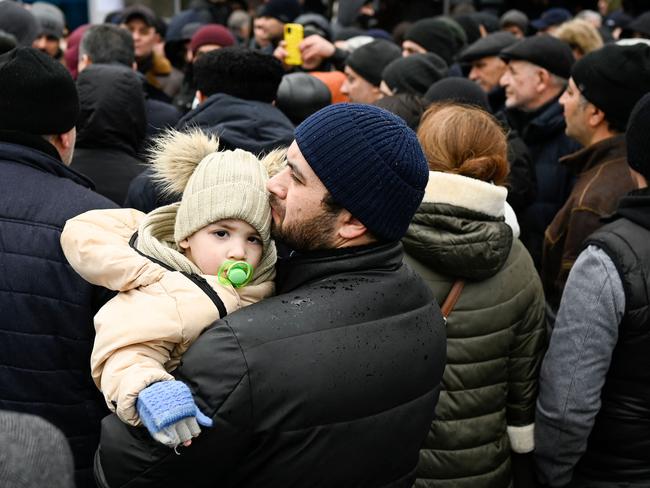 A man holds his child as families, who fled Ukraine due to the Russian invasion, wait to enter a refugee camp in the Moldovan capital Chisinau. Picture: AFP