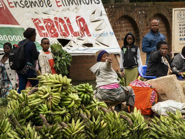 Women sell bananas by an Ebola awareness poster reading ‘together let's eliminate Ebola’ in Beni. Picture: AP