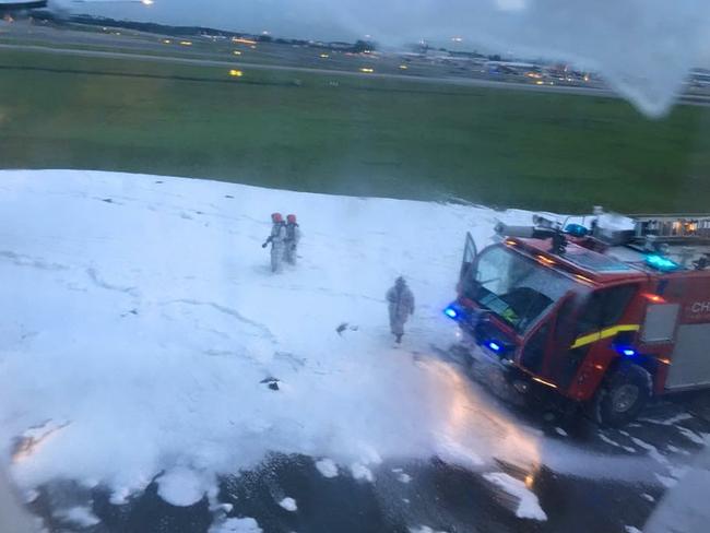 An image captured through a plane window of fire crews using foam to extinguish the blaze. Picture: Lee Bee Yee/AFP