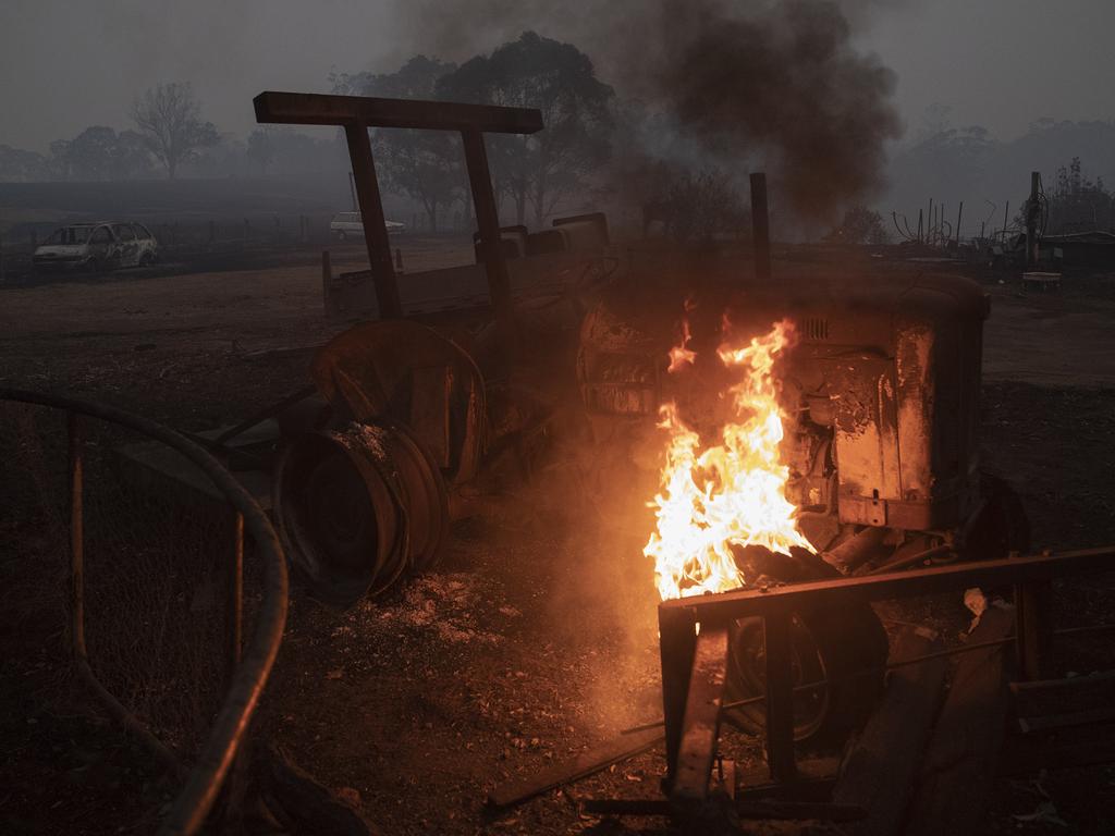 A tractor still on fire today in the backyard of a destroyed property in Cobargo. Picture: Gary Ramage