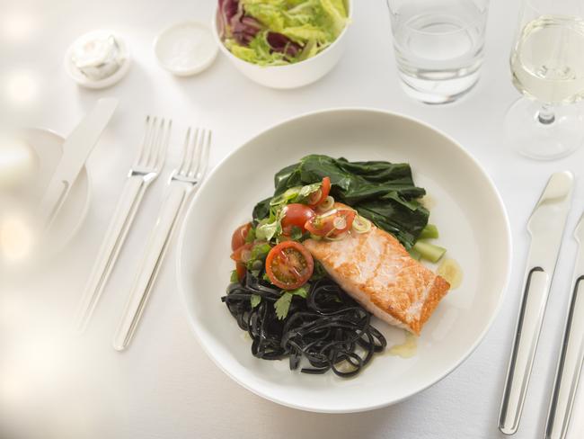 Grilled salmon with chilli, garlic, cherry tomatoes and squid ink noodles will return to the Qantas first class menu. Picture: Qantas