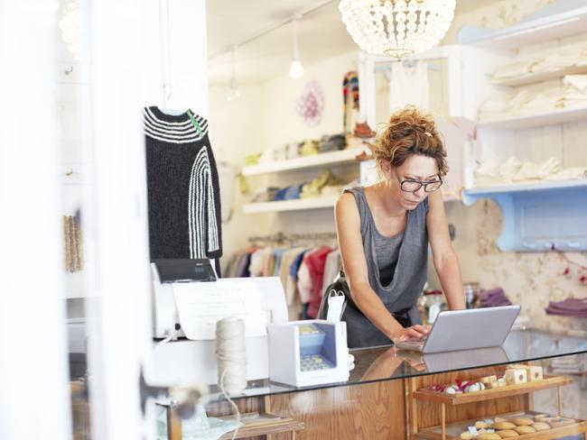 Mature saleswoman using a laptop in a small boutique