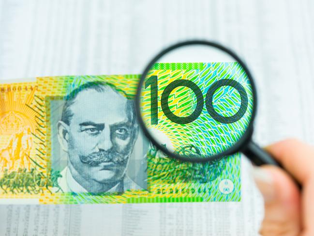 Stock Photo of Australian Money, magnifying glass with $100 note and share market data, tables, investing