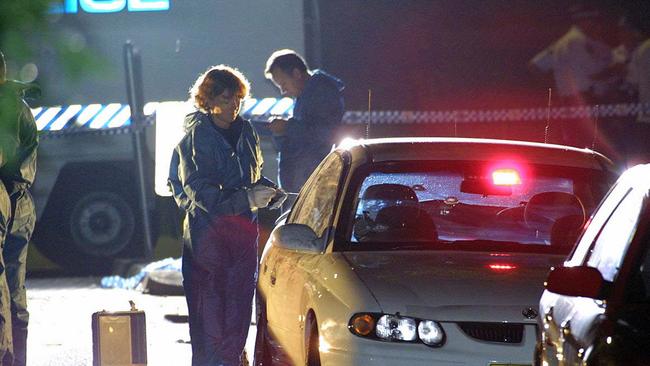 Bullet holes can be seen in the windscreen of Glenn McEnallay’s car as officers work the crime scene. Picture: Bill Hearne