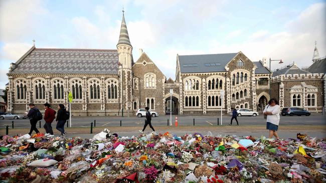 People walk past flowers and tributes displayed in memory of the twin mosque massacre victims outside the Botanical Gardens in Christchurch in 2019. Picture: AFP