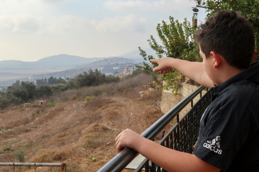 A child points to the border with Israel from his home in Qlayaa, Lebanon