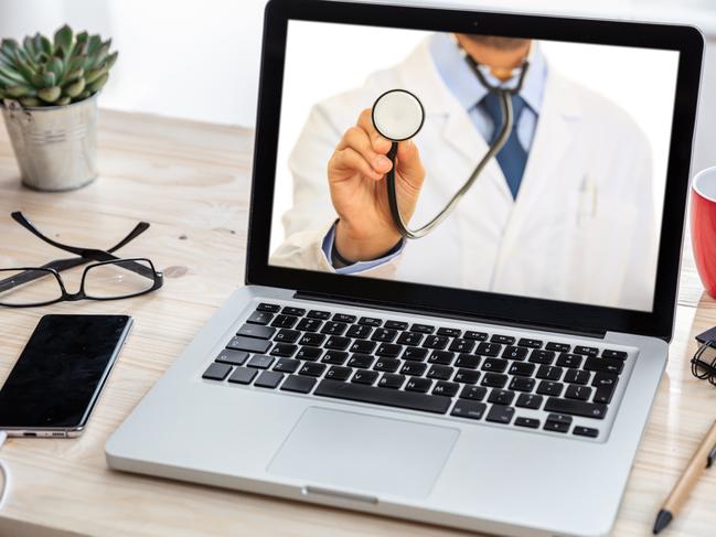 Telemedicine, online medical care concept. Doctor GP with a stethoscope on a laptop screen, office desk background