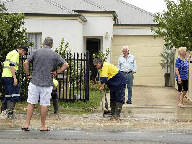 SA Water workers try to stop the flooding as residents watch, after a water main burst in Clairville Rd, Campbelltown. Picture: Bianca De Marchi