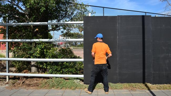 Workers erect black boards around a derelict site at one of Melbourne’s tourist gateways. Picture: Eugene Hyland